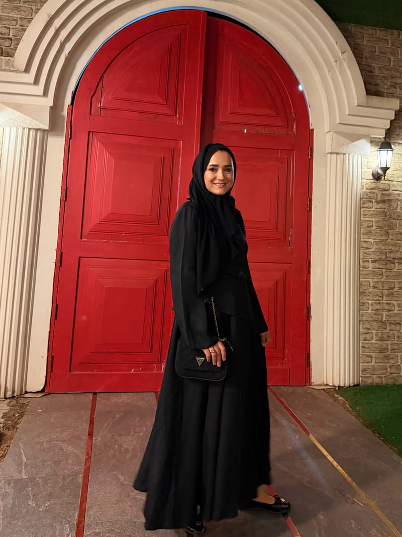 Kırmızı kemerli kapının önünde siyah takım